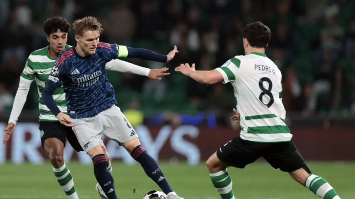 Martin Odegaard dibayangi Pedro Goncalves dan Eduardo Quaresma dalam pertandingan leg pertama perempat final Liga Champions
antara Sporting CP vs Arsenal di stadion Jose Alvalade di Lisbon pada 7 April 2026. (Foto oleh PATRICIA DE MELO MOREIRA / AFP)
(AFP/PATRICIA DE MELO MOREIRA)