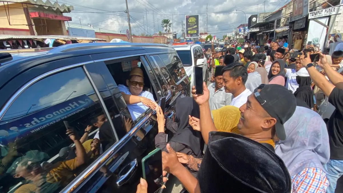 DISAMBUT: Warga bersalaman dengan Haji Her saat melintas di Jalan Raya Blega, Minggu (12/4). JUPRI/JRPM