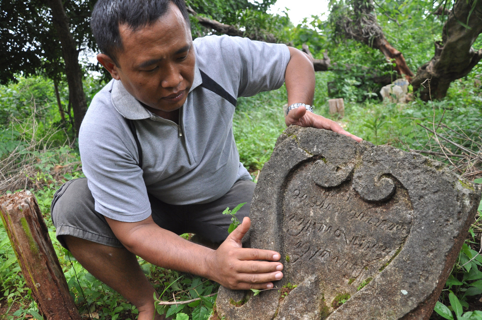 Hari Winarko, Kepala Desa Prunggahan Wetan, Kecamatan Semanding, Kabupaten Tuban, Jawa Timur membersihkan batu nisan makam Barat Ketigo.