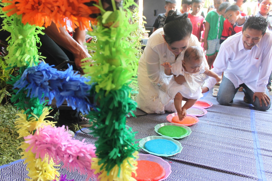Menapaki tujuh jadah atau ketan warna-warni, prosesi yang melambangkan kelak kalau dewasa bayi ini ombo jangkahe.