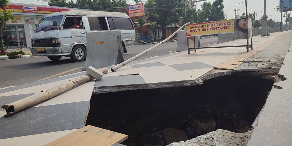 Lubang besar di trotoar Jalan RE Martadinata akibat sering dihantam ombak. Semakin hari, kondisinya semakin parah.