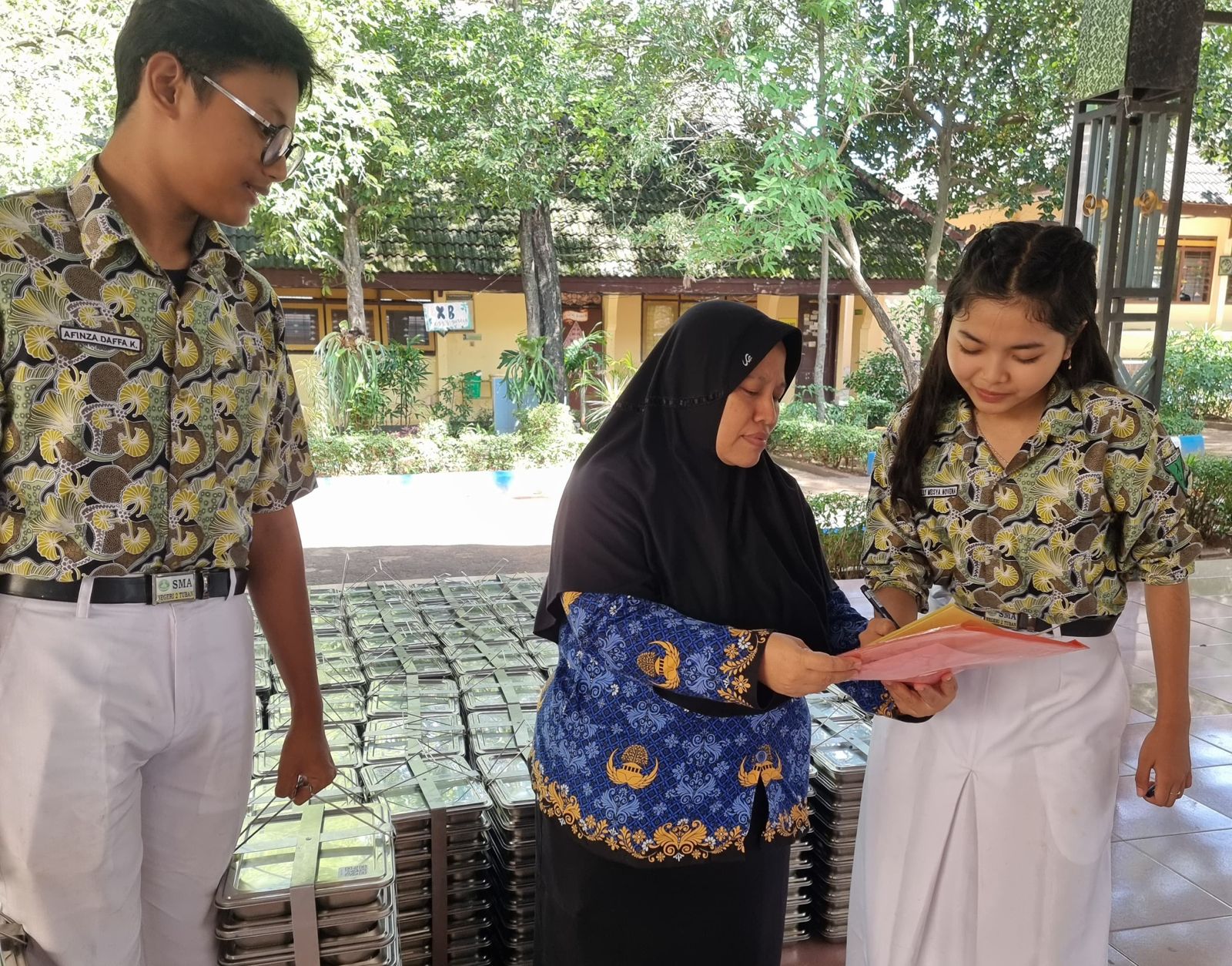Guru dan siswa SMAN 2 Tuban saling kerja sama melakukan distribusi Makan Bergizi Gratis ke tiap kelas.