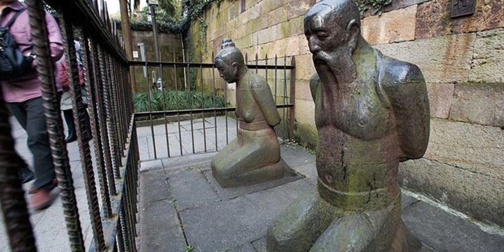 Patung Qin Hui dan istrinya berlutut di depan makam Jenderal Yue Fei di Hangzhou, Tiongkok. Selama berabad-abad, warga yang berziarah kerap meludah atau menendang patung ini sebagai simbol penolakan