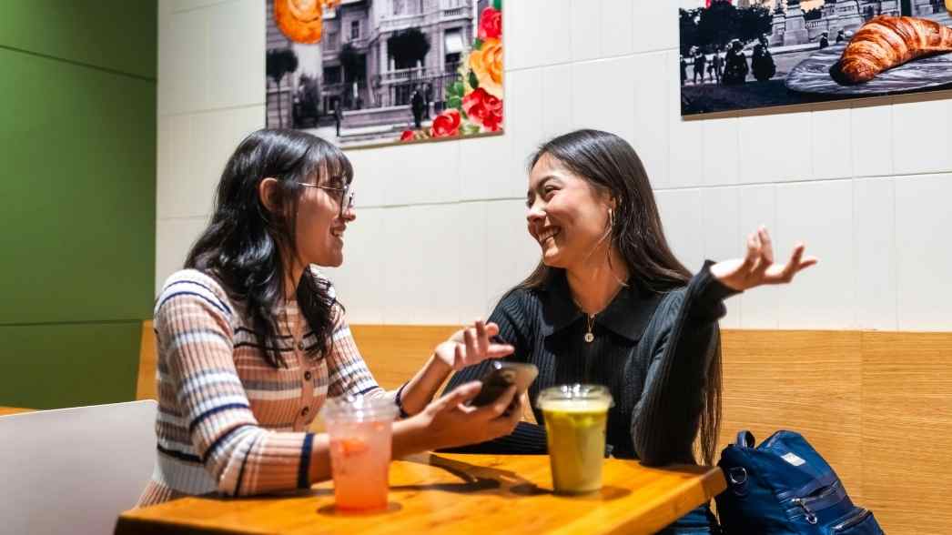 Ilustrasi dua teman sedang mengobrol di kafe, situasi yang sering menjadi ruang munculnya dinamika sosial seperti perilaku &lsquo;pick me&rsquo; dalam pergaulan sehari-hari