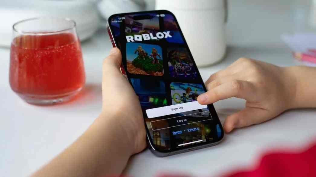 Seorang anak membuka aplikasi Roblox di ponsel, sementara platform tersebut bersiap menerapkan aturan verifikasi usia berbasis wajah dan pembatasan chat untuk meningkatkan keamanan pengguna muda.