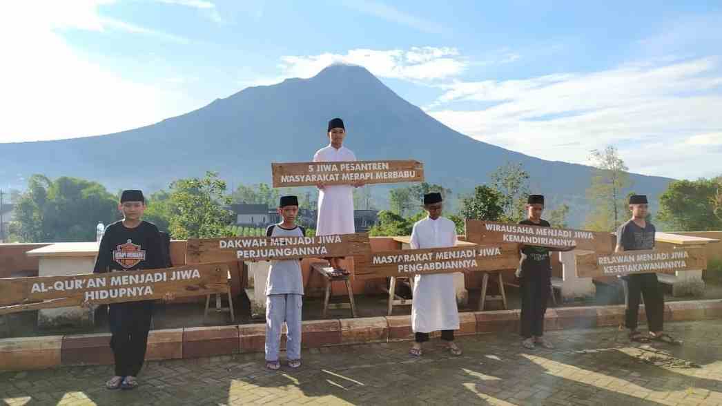 Para santri berdiri memegang papan nilai &ldquo;5 Jiwa Pesantren Masyarakat Merapi Merbabu&rdquo; dengan latar megah Gunung Merapi, menggambarkan semangat dakwah, pengabdian, dan kemandirian yang terus dijaga