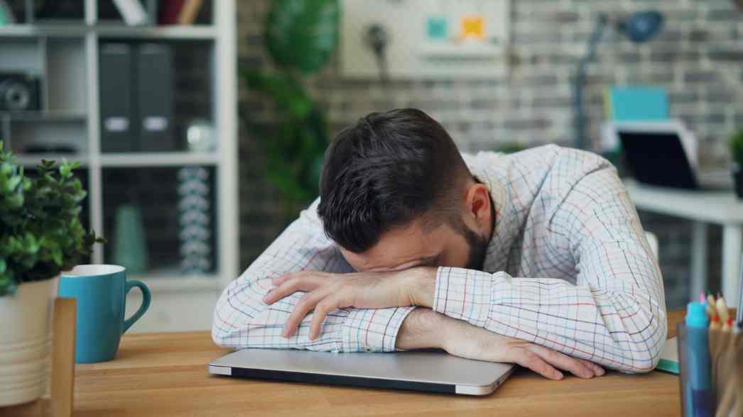 Seorang pria tampak kelelahan dan tertidur di atas laptop, menggambarkan kondisi tubuh yang dipaksa bekerja terus-menerus hingga mengabaikan sinyal penting seperti lelah dan penurunan energi.