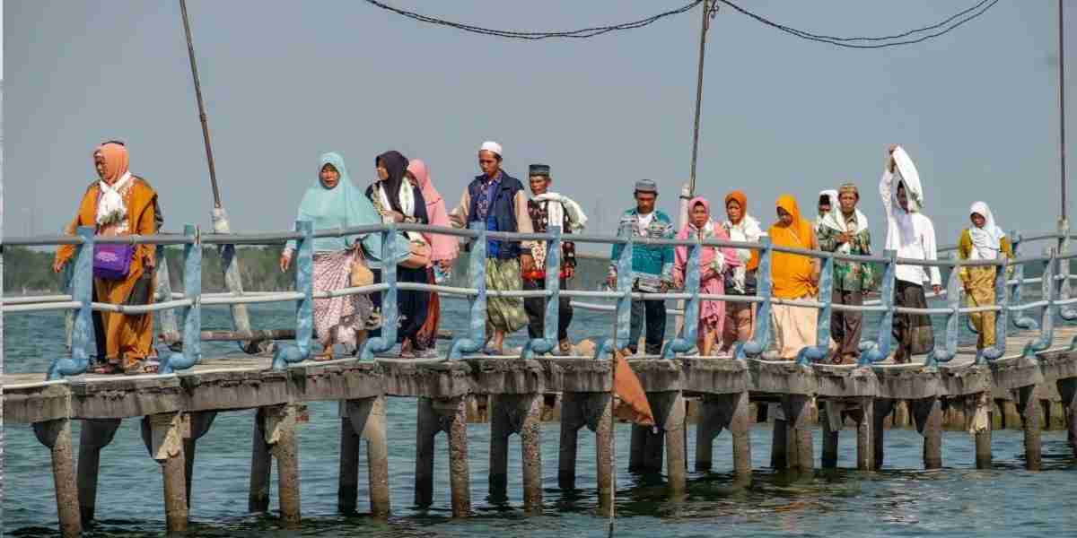 Peziarah berjalan di atas jembatan menuju kawasan makam Syekh Abdullah Mudzakir di Pantai Sayung, Demak yang dikelilingi laut.