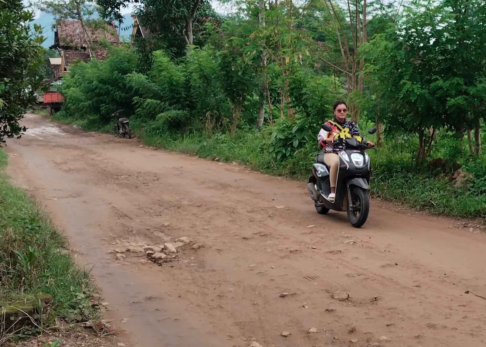 Seorang warga sedang melintasi jalan Desa Gador, Kecamatan Durenan yang kini hanya sisa tanah dan bebatuan