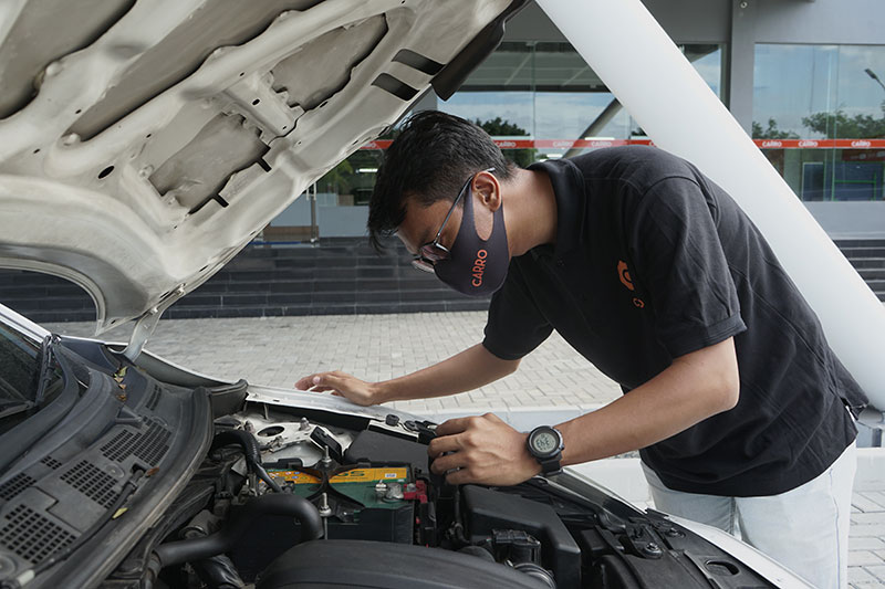 Mekanik sedang mengecek kondisi mobil  bekas apakah layak untuk dibeli
