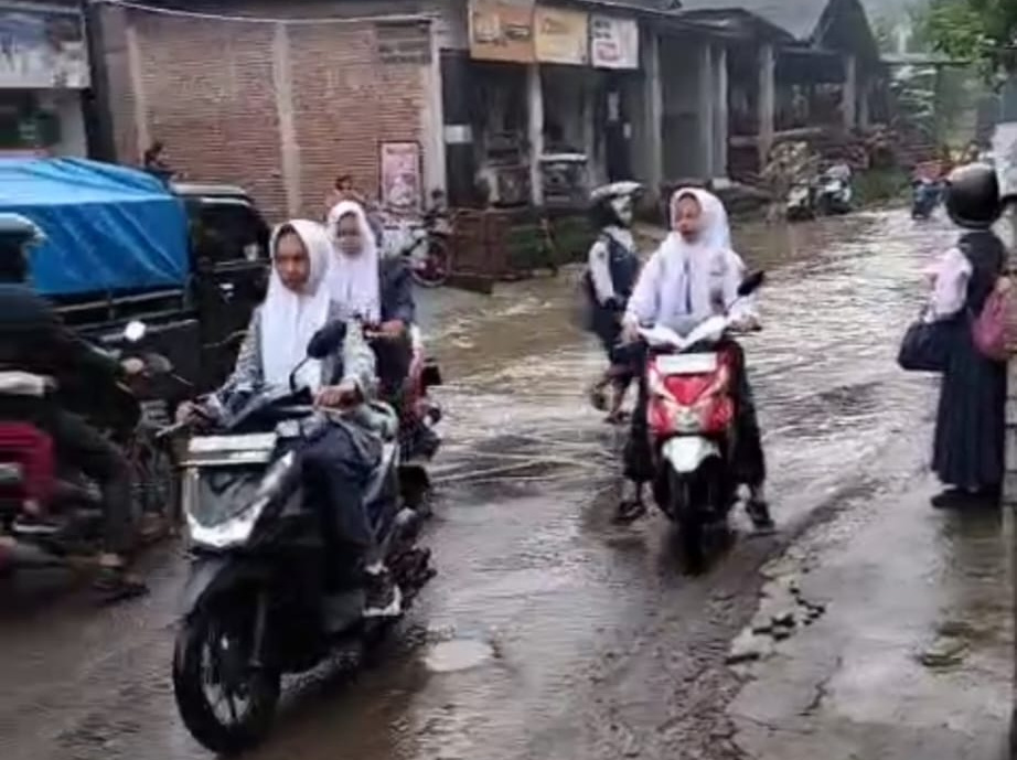 Warga melintas di jalan Kampak- Sebo yang jadi sungai saat hujan