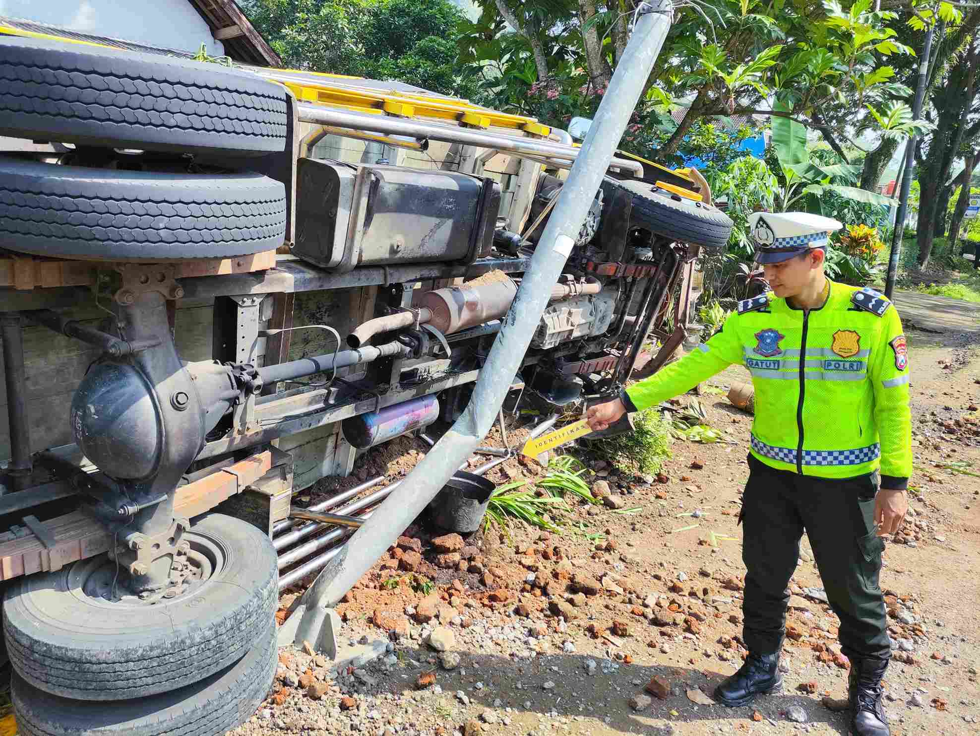 Tim Polres Trenggalek saat memeriksa kondisi truk bermuatan telur yang terguling usai tabrak pagar rumah milik warga.