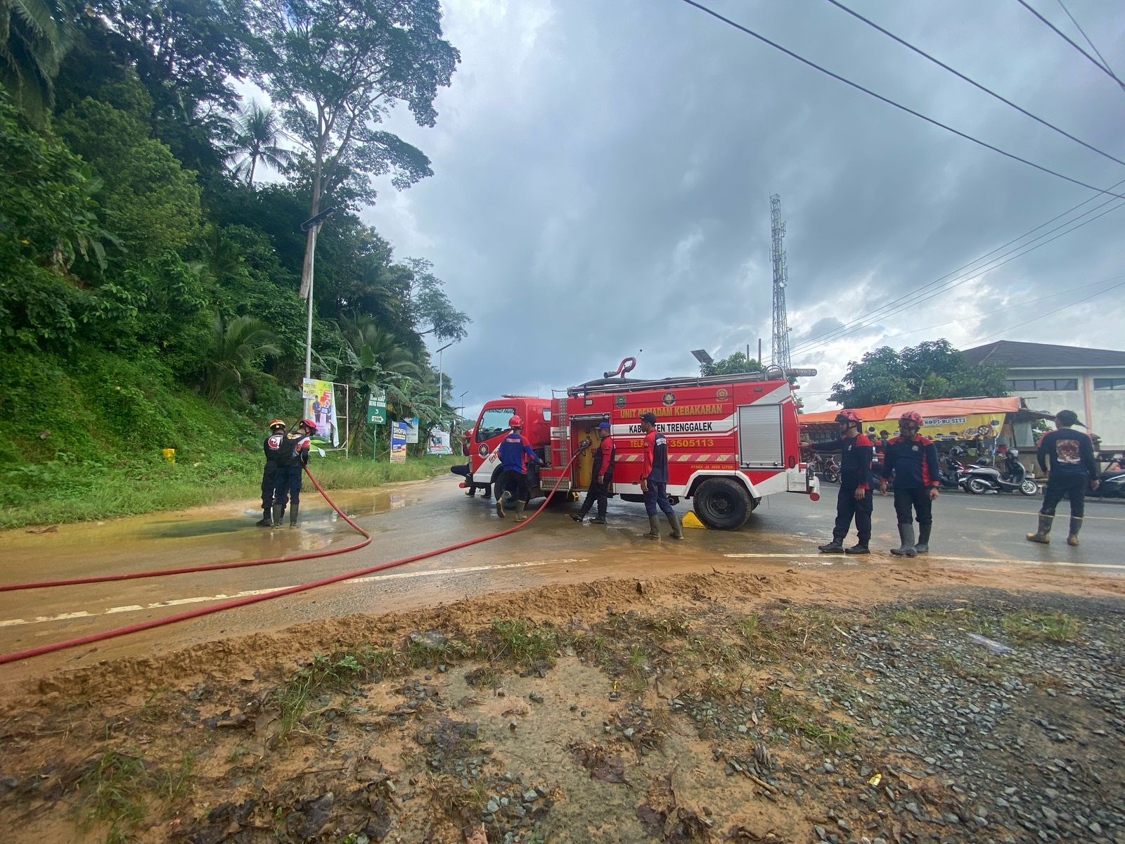 Petugas damkar menyemprot material banjir yang melanda di Desa Tasikmadu, Watulimo