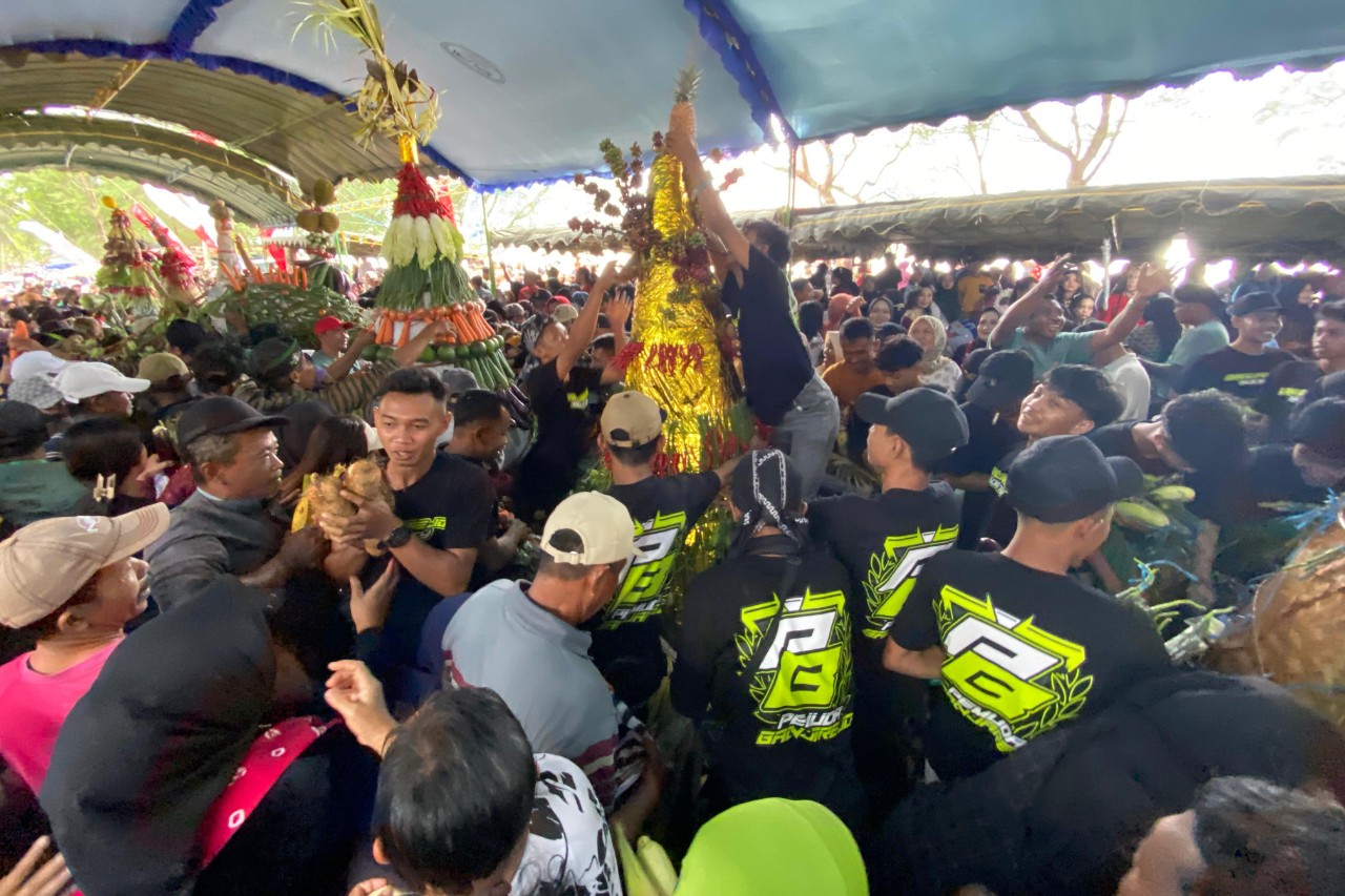 Warga berebut hasil bumi dari 9 tumpeng yang diarak warga pada Labuh Laut Sembonyo Pantai Cengkrong, Minggu (29/6/2025). (DR PERDANA/RADAR TRENGGALEK)