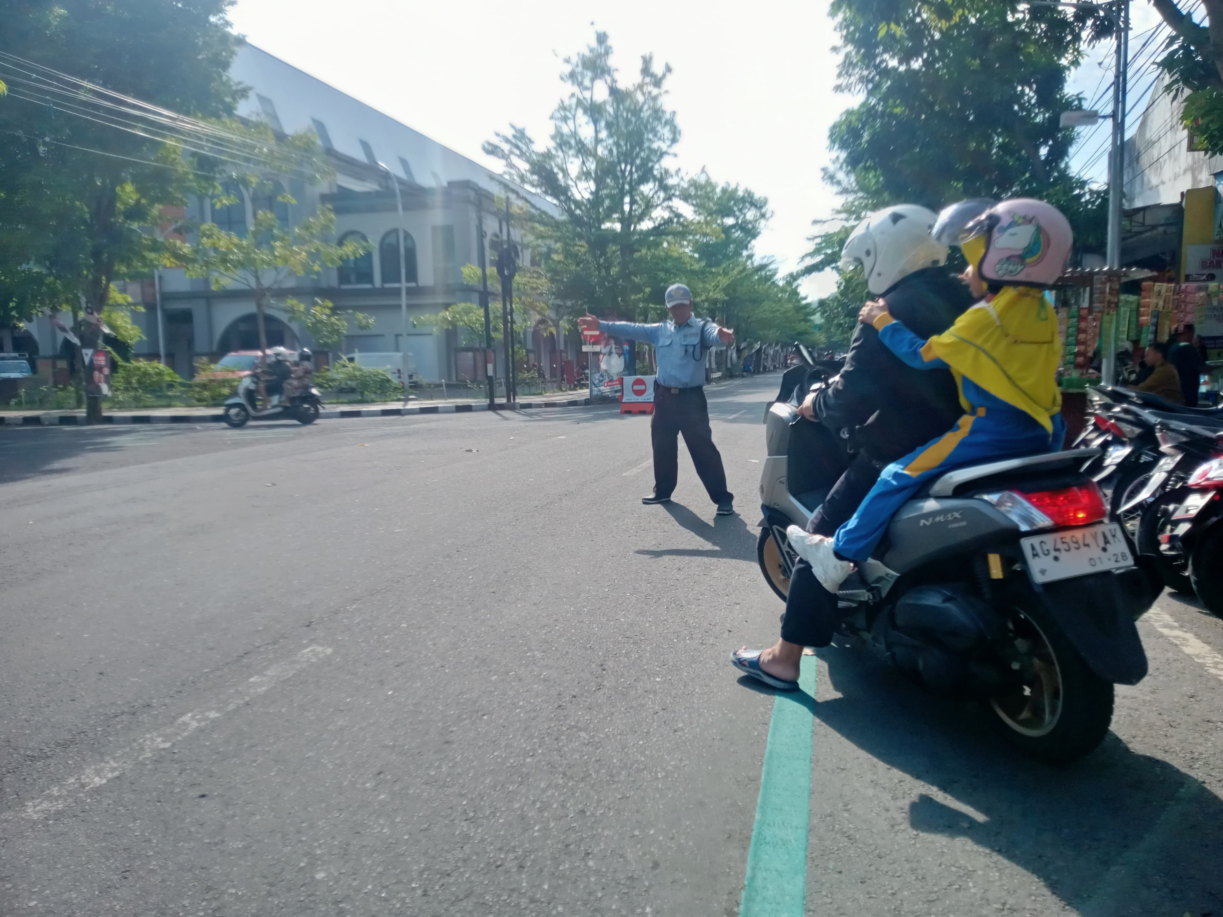 Jukir di Trenggalek memberi jalan pengguna motor untuk menyebrang
