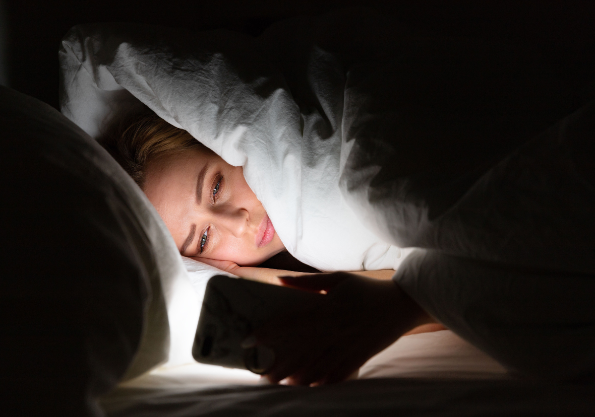 Ilustrasi seseorang sulit tidur karena paparan layar gadget di malam hari.