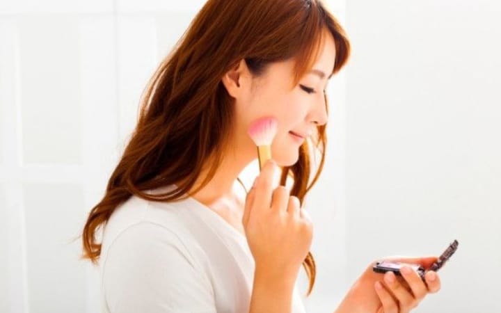 Seorang wanita sedang merias wajah dengan make up agar hasilnya tahan lama.