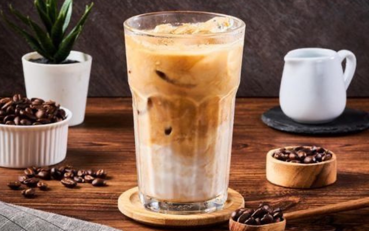 Secangkir es kopi susu dengan gradasi warna yang menggugah peminat kopi.