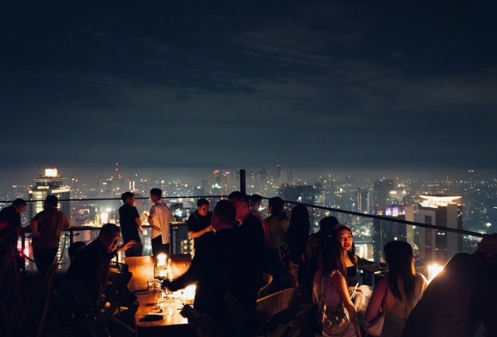 Suasana malam di rooftop caf&eacute; dengan pemandangan kota yang gemerlap, tempat ideal untuk bersantai menikmati angin malam dan keindahan cahaya lampu kota.