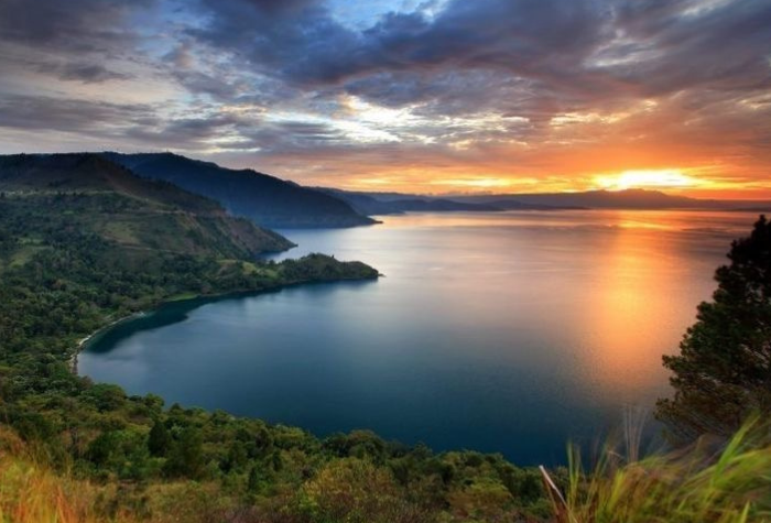 Pemandangan danau alami Indonesia dengan air jernih dan latar pegunungan hijau menciptakan suasana tenang yang menyejukkan mata dan jiwa.