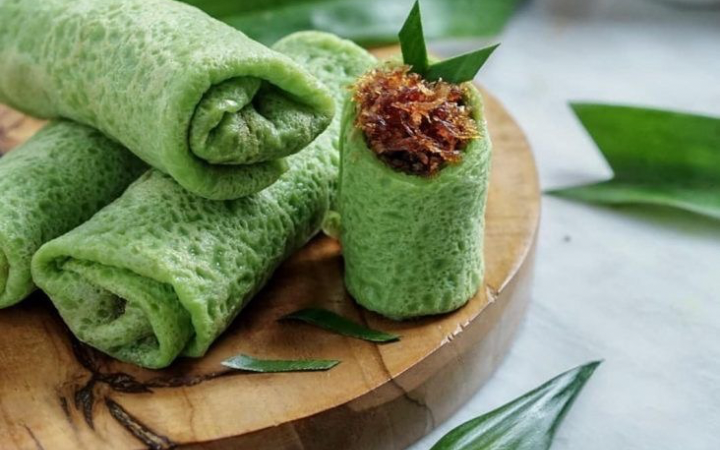 Dadar gulung berwarna hijau lembut dengan isian kelapa manis menggambarkan kehangatan cita rasa tradisional Indonesia yang tetap digemari.