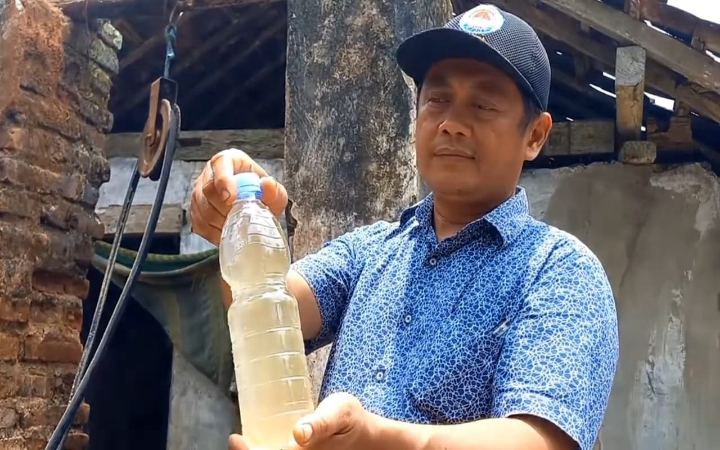 Salah seorang warga Desa Prambon, Kecamatan Tugu, Kabupaten Trenggalek, menunjukkan air keruh yang diambil dari sumur.