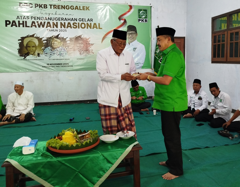MENJADI TELADAN : Ketua DPC PKB Trenggalek Sukarodin, memberikan potongan tumpeng kepada Ketua Dewan Syoro DPC PKB Trenggalek KH rhasyim pada tasyakuran penetapan tiga tokoh sebagai pahlawan nasional.