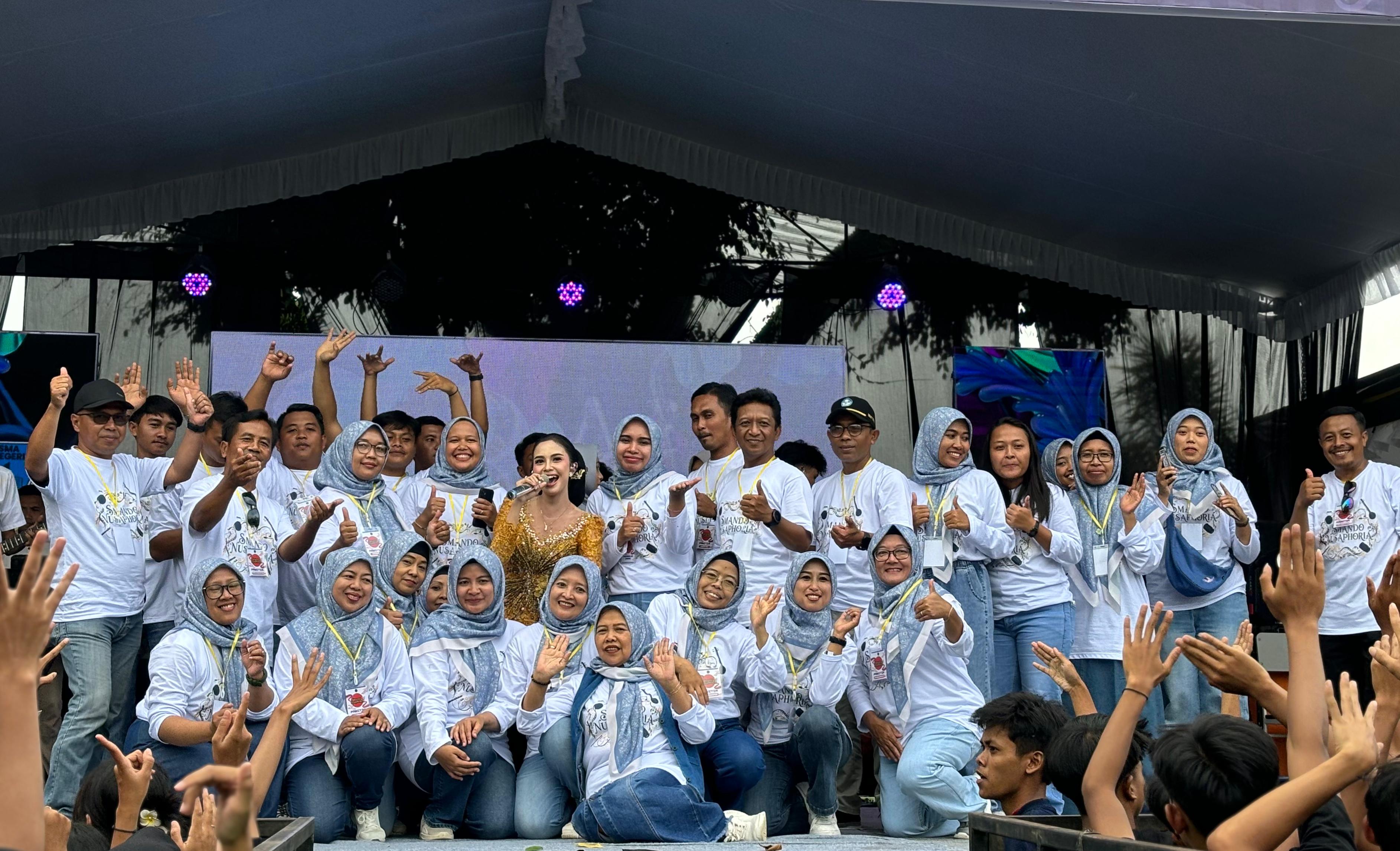 Panitia, guru, staf tenaga kependidikan foto bersama dengan bintang tamu utama di panggung.