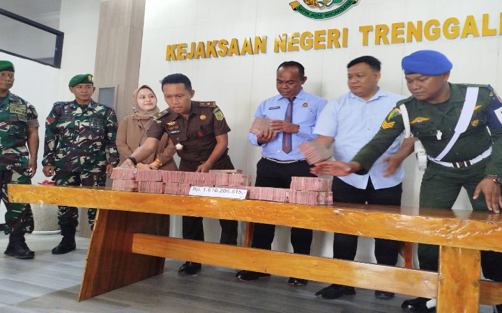 Kepala Kejari Trenggalek La Ode Muhammad Nusrim (tengah berdasi), bersama tim dan sejumlah pihak, menyerahkan uang pengembalian kerugian negara pada Selasa (20/1/2026).