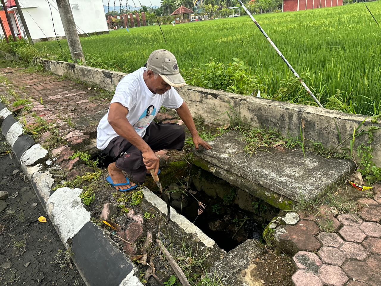 Potret Seseorang sedang memeriksa dan membersihan drainase