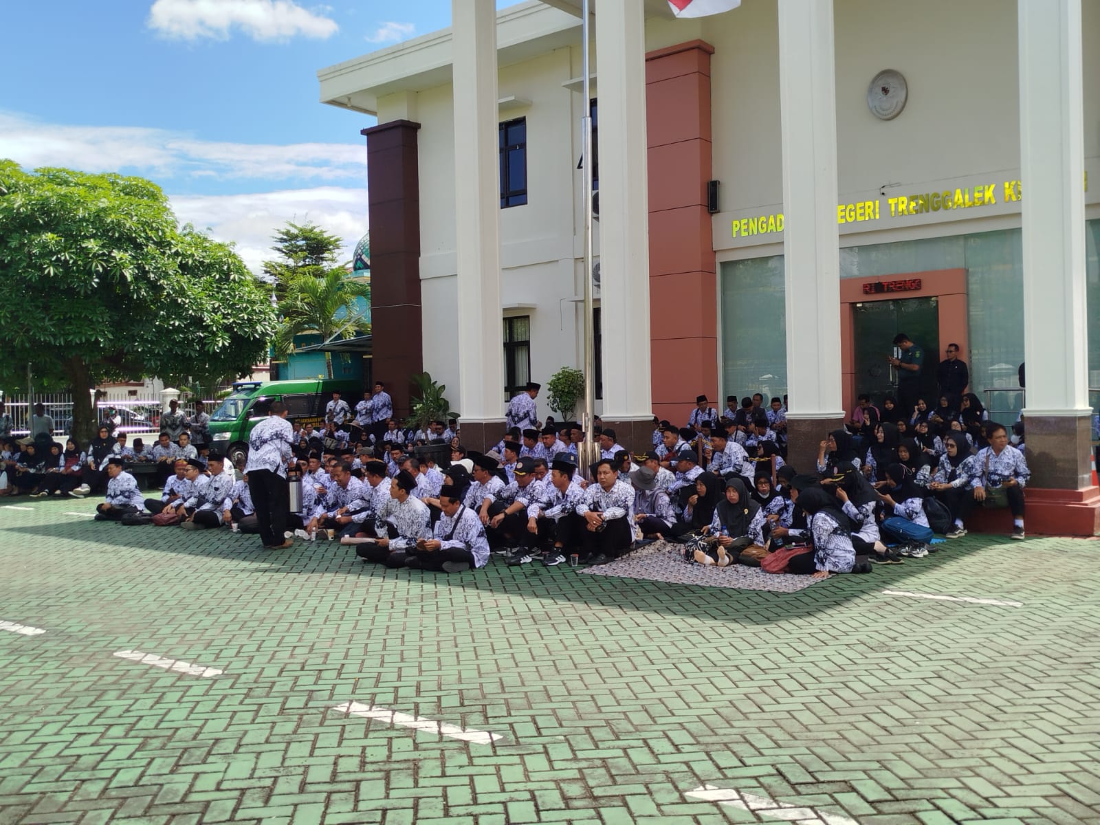 Para tamu yang tidak kebagian tempat duduk menyasikan sidang kasus pemukulan guru dari luar ruangan PN Trenggalek, Selasa (3/2/2026).