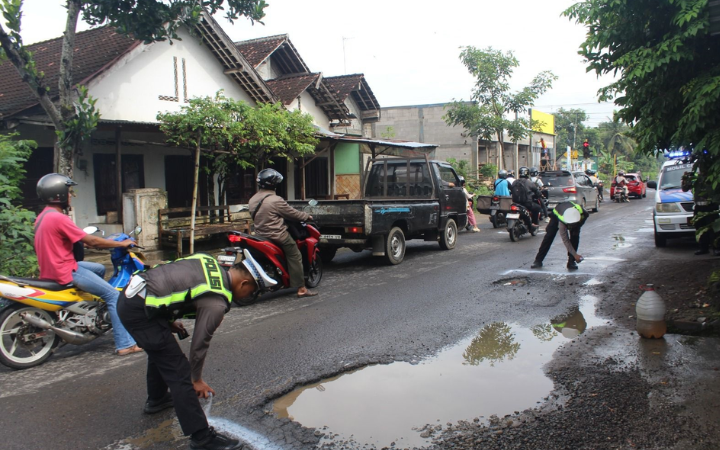 HATI-HATI: Polisi memberi tanda untuk pemetaan jalan berlubang di area simpang empat Sumberingin hingga simpang tiga Ngetal.