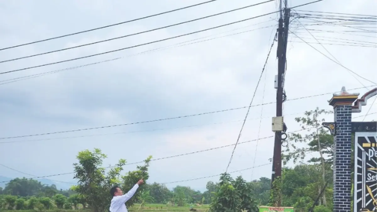 HARUS DITATA: Kepala Desa Salamrejo, Kecamatan Karangan, Ibnu Jadid, menunjukkan kabel semrawut di desa setempat.(GUNAWAN/RADAR TRENGGALEK)