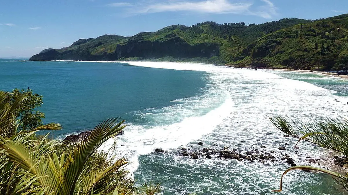 Pantai Menganti Kebumen menawarkan pasir putih, tebing karst, Geopark internasional, Jembatan Merah, dan panorama Samudra Hindia yang memukau (Pinterest).