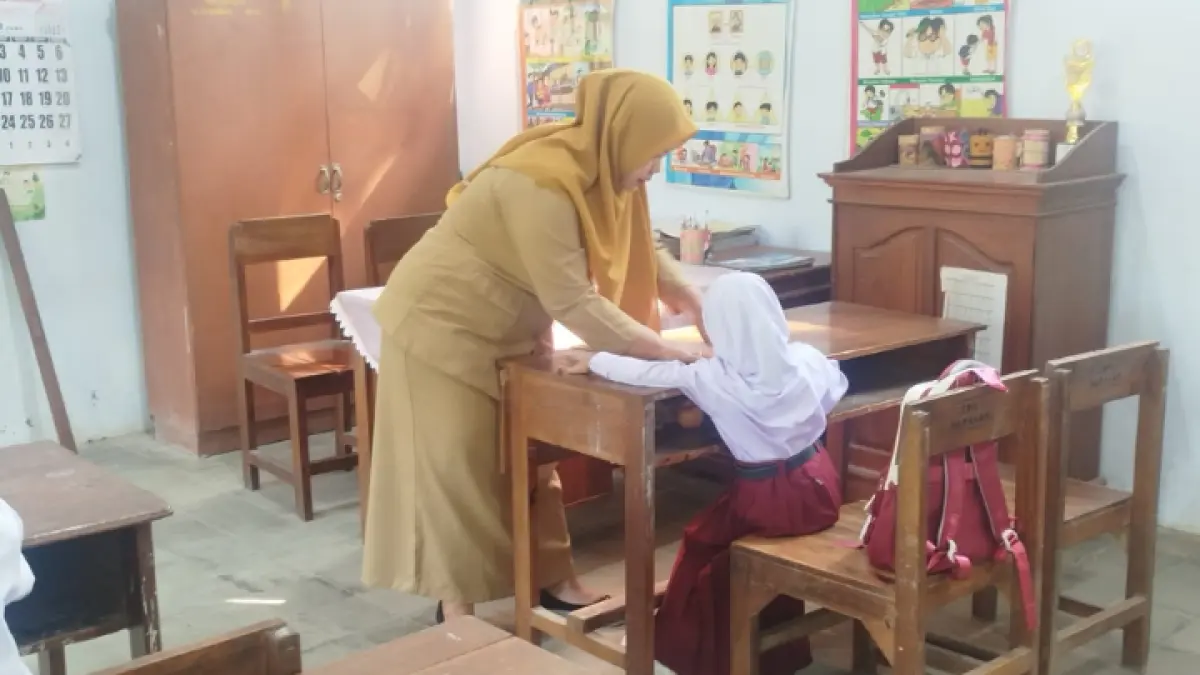 MENGABDI: Guru SDN 2 Parakan saat melaksanakan MPLS terhadap dua siswa baru.(ZAKI JAZAI/ RADAR TRENGGALEK)