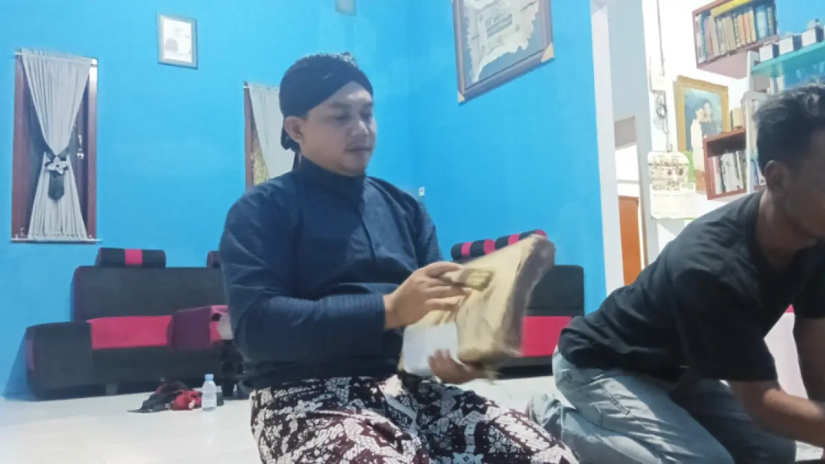 PERTAHANKAN TRADISI: Harmadji memperlihatkan naskah kuno miliknya yang masuk registrasi perpustakaan nasional sebelum di jamas.(ZAKI JAZAI/ RADAR TRENGGALEK)