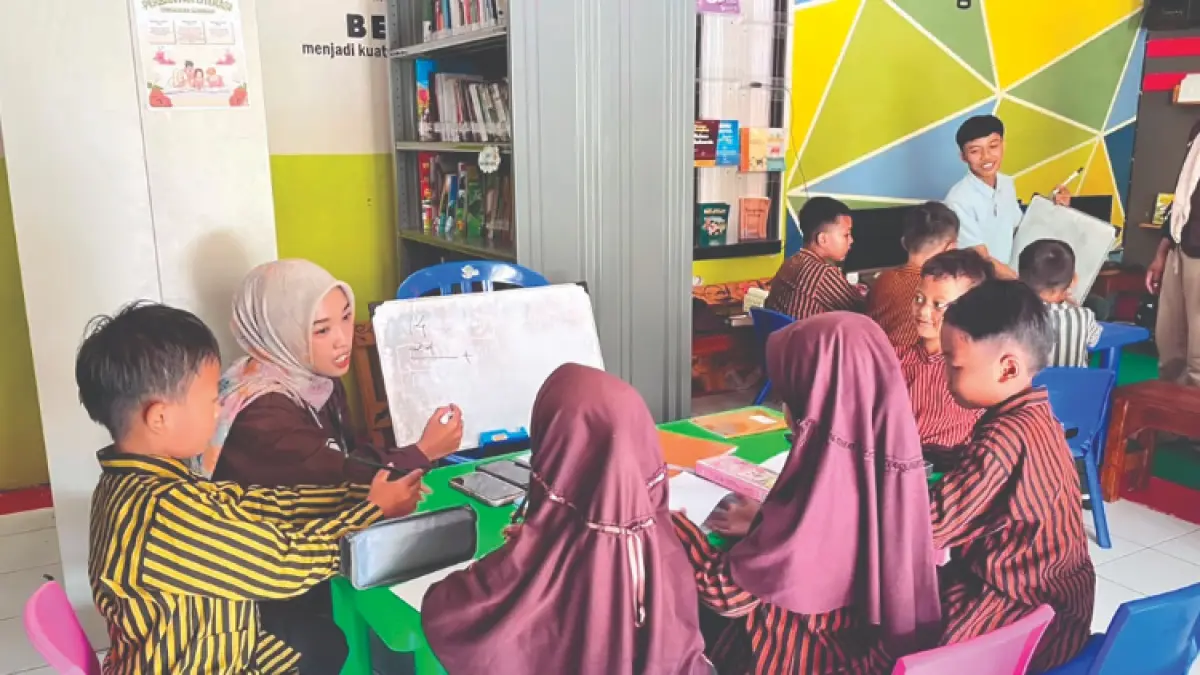 BAGI ILMU: Mahasiswa ketika memberikan bimbingan di perpusdes, Desa Buluagung, Kecamatan Karangan.(GUNAWAN/RADAR TRENGGALEK)