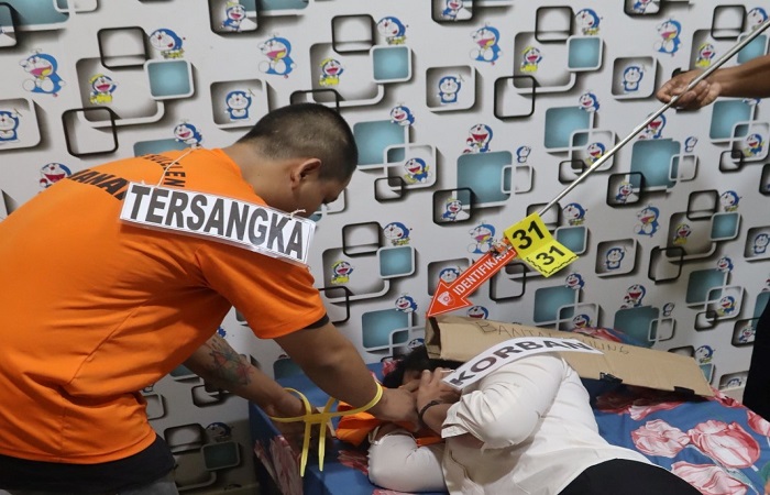 Tersangka Aan memeragakan adegan pembunuhan nomor 31, dengan mendekap bibir dan hidung korban Ketut Parmi.