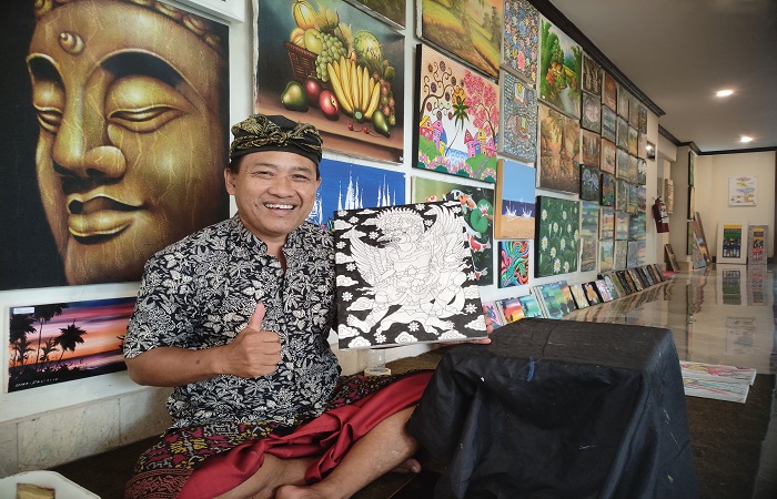 Nyoman Dira di tengah kesibukannya menjual lukisan.