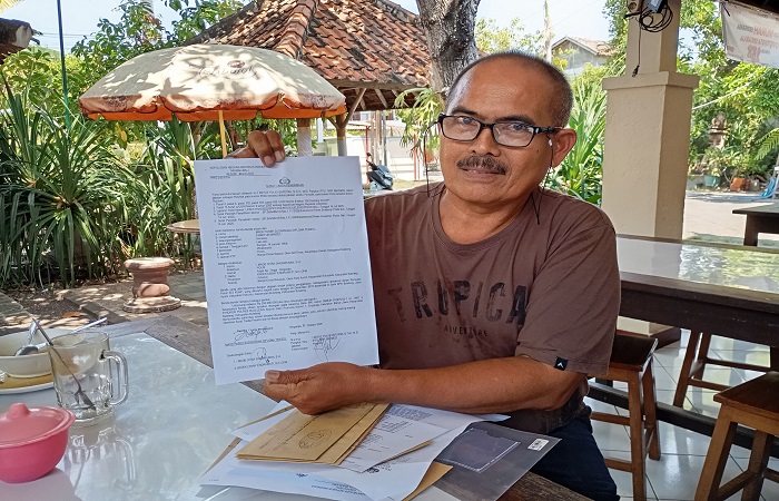 Made Pasek Sudarsana menunjukkan surat dari polisi berkaitan dengan laporan yang dilayangkan kepadanya dari adiknya sendiri, GPS.