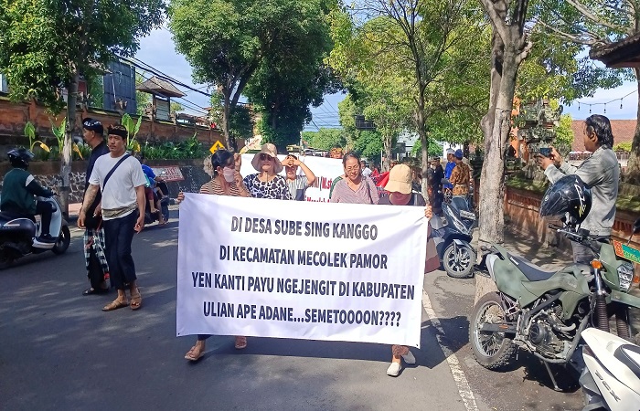 Krama Desa Adat Banyuasri menyuarakan aspirasi mereka dengan membentangkan spanduk di lokasi paruman pemilihan Ketua MDA Buleleng.