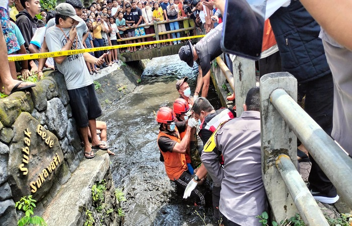 Petugas mengangkat jasad korban dari saluran irigasi menuju mobil ambulans. Korban diketahui bernama I Made Merta, yang akrab disapa Mangku Anggun.