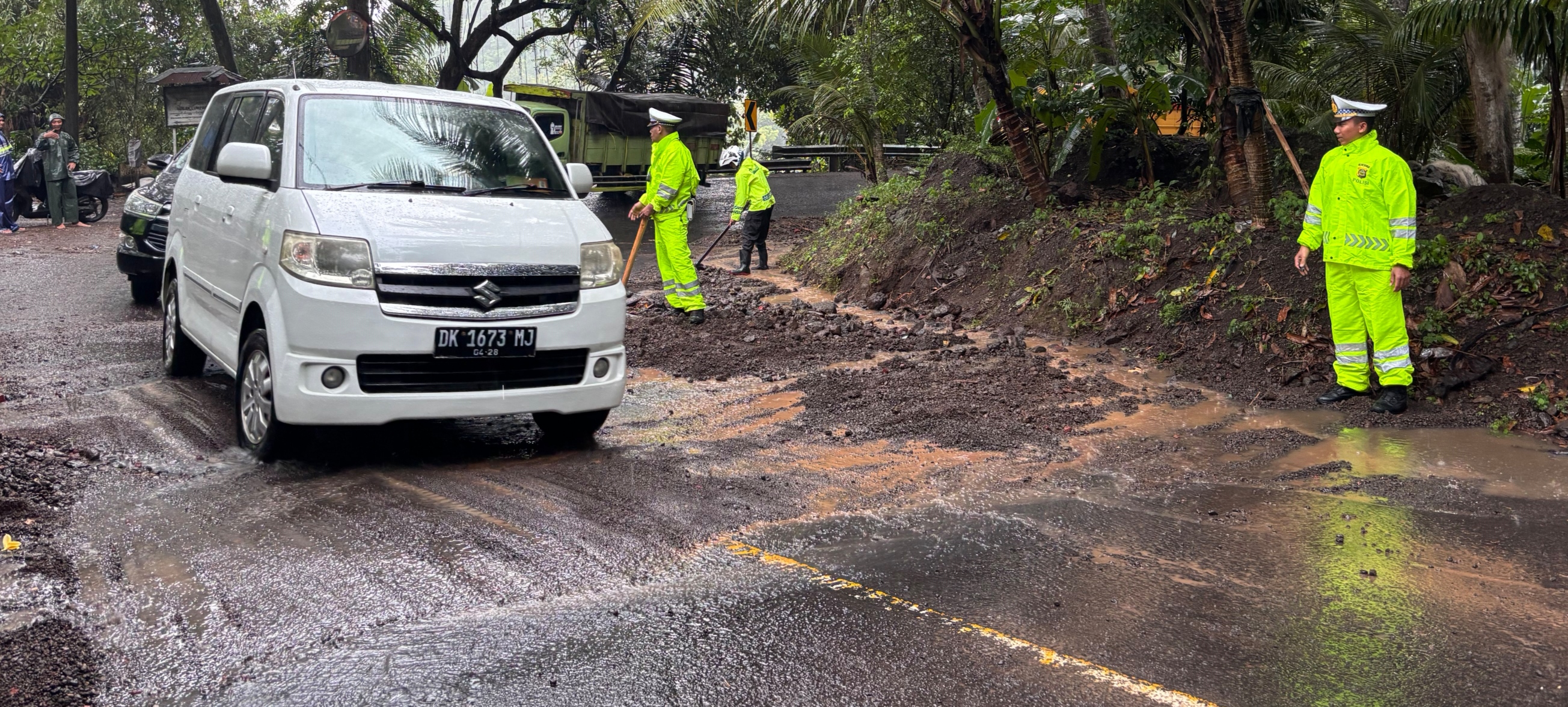 Petugas kepolisian saat melakukan pembersihan material longsor yang menutup badan jalan di Sanghyang Ambu, pada Minggu (11/1) kemarin.