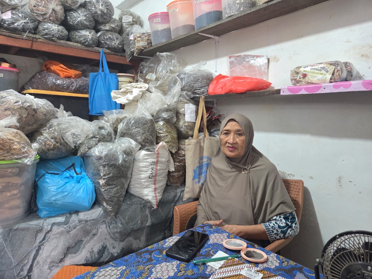 Halimah, 70, tahun duduk termangu di balik kiosnya berukuran 3x4 meter. Dia mengaku sudah beberapa hari sepi pembeli karena banjir di Denpasar. 