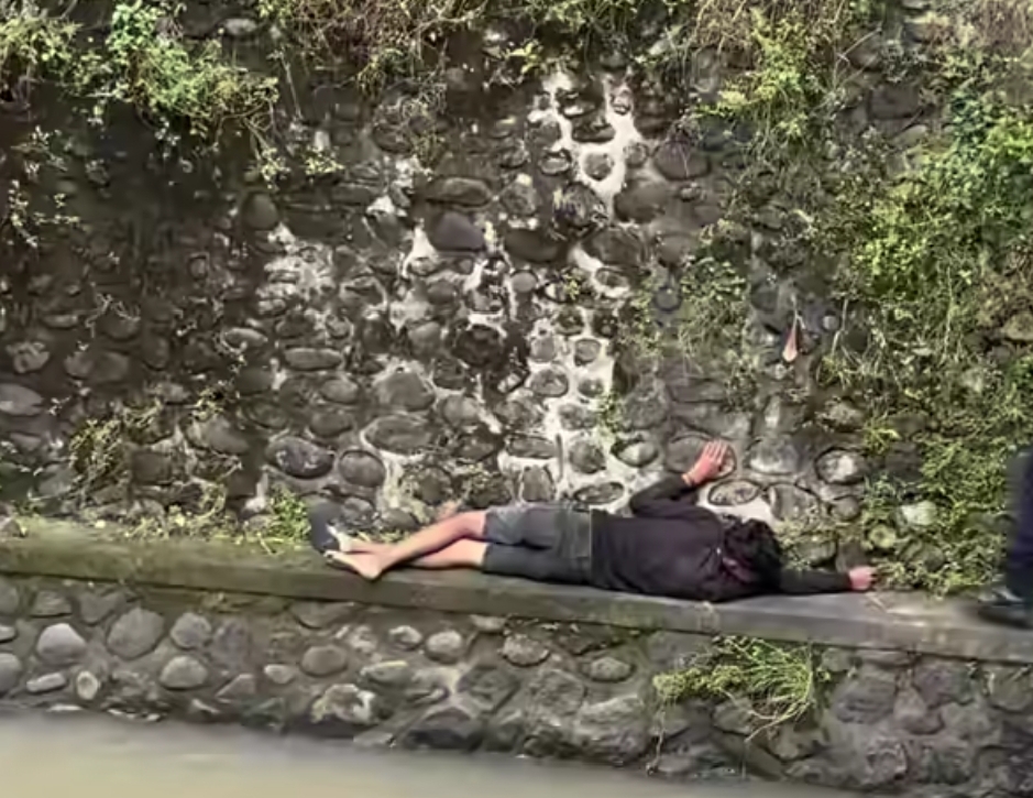 Seorang pria berinisial NS,28, (baju hitam), asal Banyuwangi, yang terjatuh ke sungai di kawasan Jalan Mataram IV Lumintang, Denpasar Utara, Minggu (1/3/2026) pagi. 