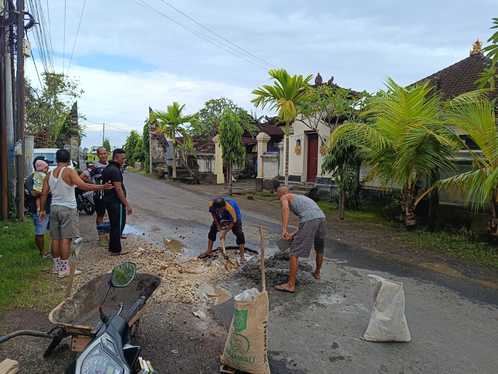 Warga Desa Nyitda Tabanan memperbaiki jalan rusak yang acap menyebabkan kecelakaan. 