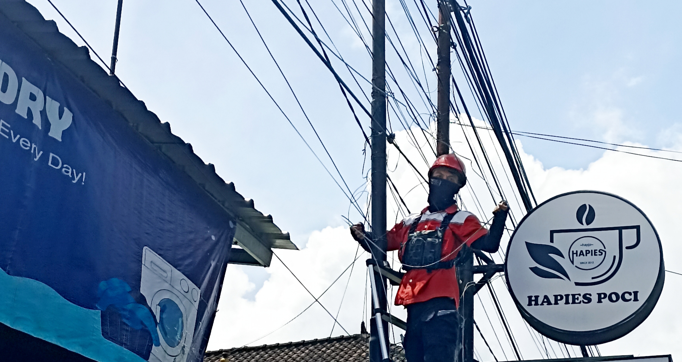 Seorang pekerja sedang memperbaiki jaringan serat kabel optik untuk layanan WiFi di kawasan Ubung.