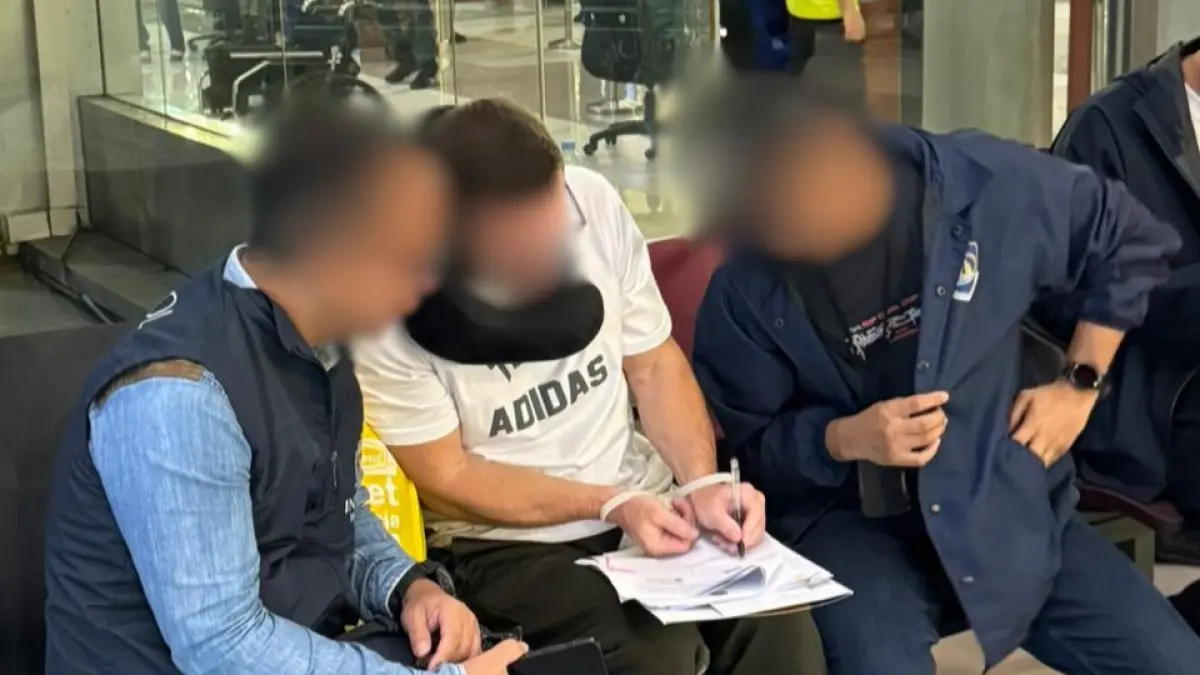 Petugas saat mengamankan buronan Interpol asal Inggris di Bandara Ngurah Rai. Pelaku diduga bos mafia pencucian uang. (Istimewa) 