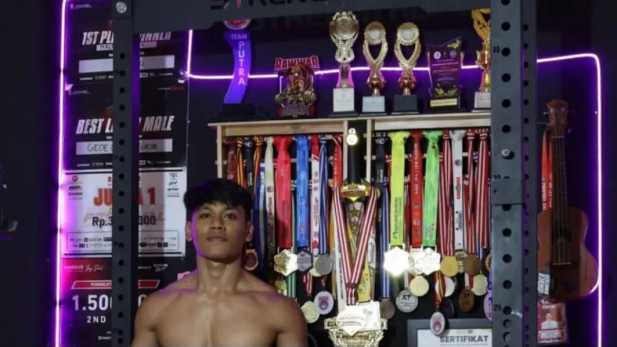 I Gede Wahyu Surya Wiguna berpose di depan deretan medali yang berhasil diraihnya. Meski ukir rekor dunia, ia gagal berlaga di kancah internasional lantaran terganjal administrasi. (Foto Istimewa) 