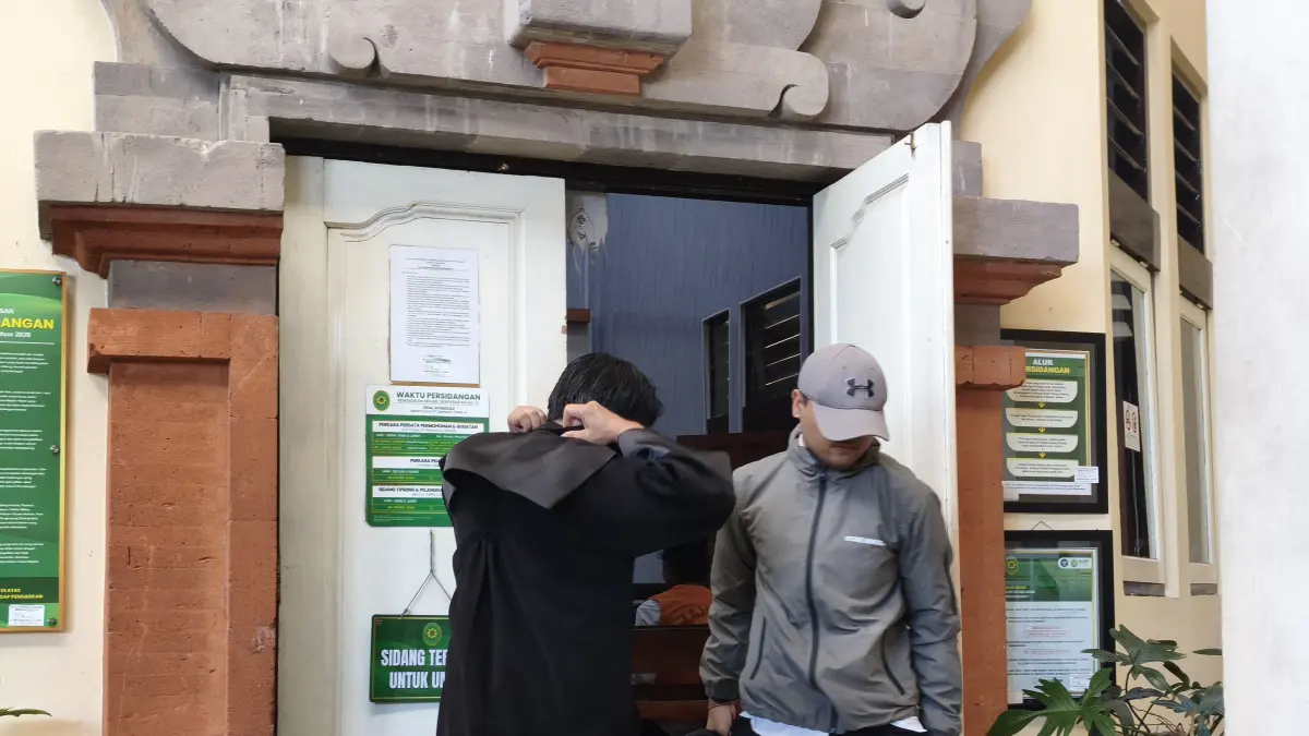 I Made Wisnu Mas Supartha (pakai topi) usai menjalani sidang di PN Denpasar, Kamis (9/4). Pemuda ini didakwa mengancam mantan pacarnya lewat WhatsApp. (Istimewa) 